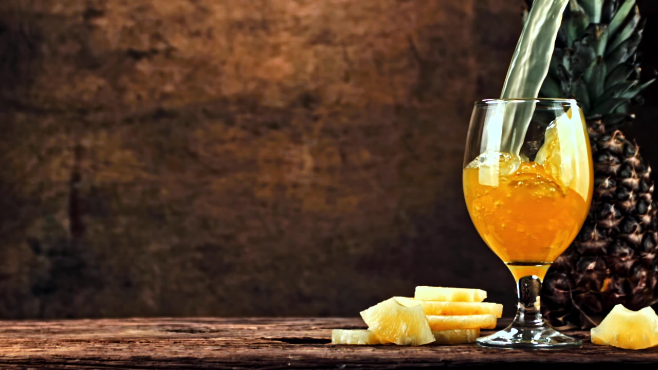 Menuangkan Jus Nanas Segar ke dalam Gelas di atas Meja Pedesaan