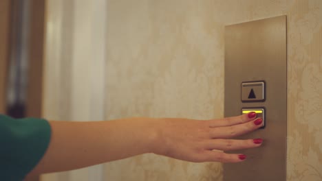 Female-hand-pushing-button-for-calling-elevator-in-apartment-corridor