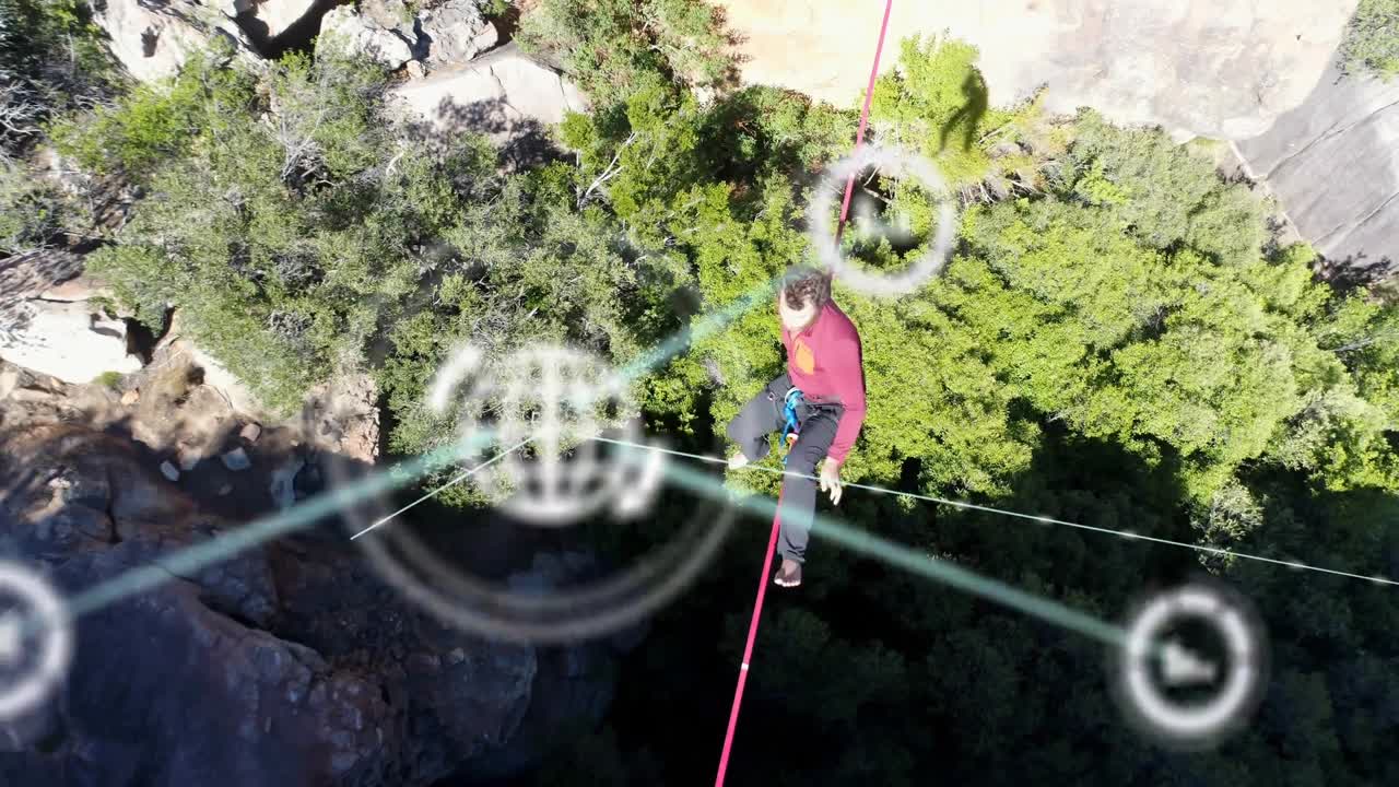 Inizio ripresa drone, highliner uomo che attraversa un canyon su una linea rossa, in equilibrio mentre i nodi AR oscurano.