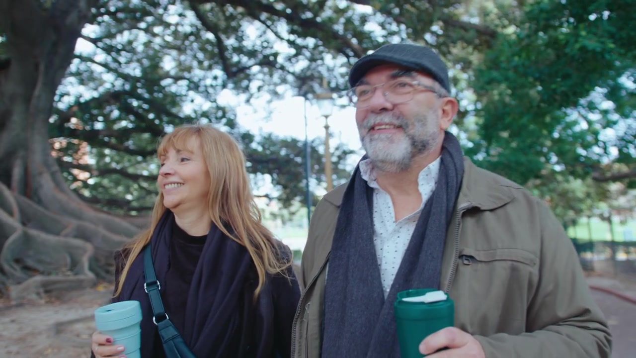 Happy Senior Couple Walking with Coffee in the Park