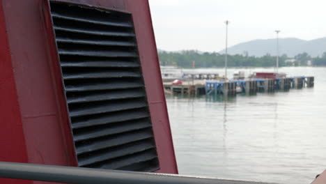 red vent of ferry with view of southeast asia pier and coast in baclground