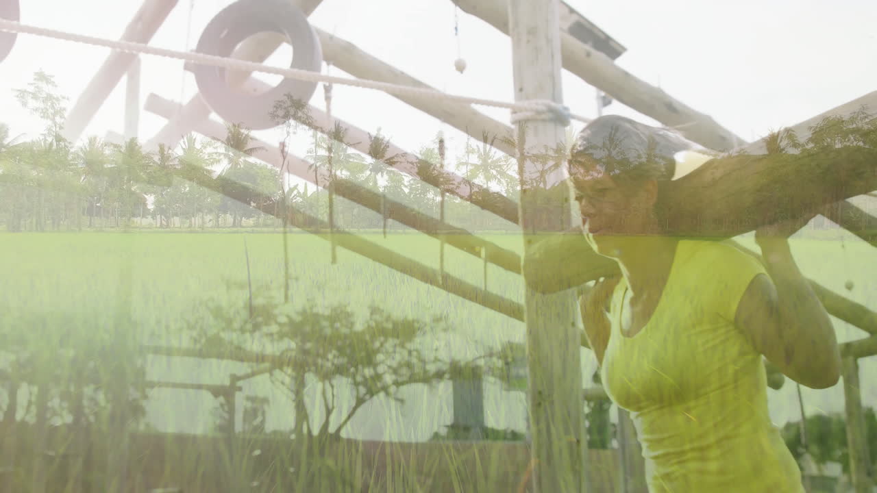 Carrying wooden beam, woman walking through lush green field with palm trees