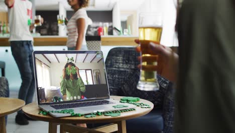 Mujer-Tomando-Cerveza-En-Una-Videollamada-Portátil-Celebrando-El-Día-De-San-Patricio-Con-Amigos