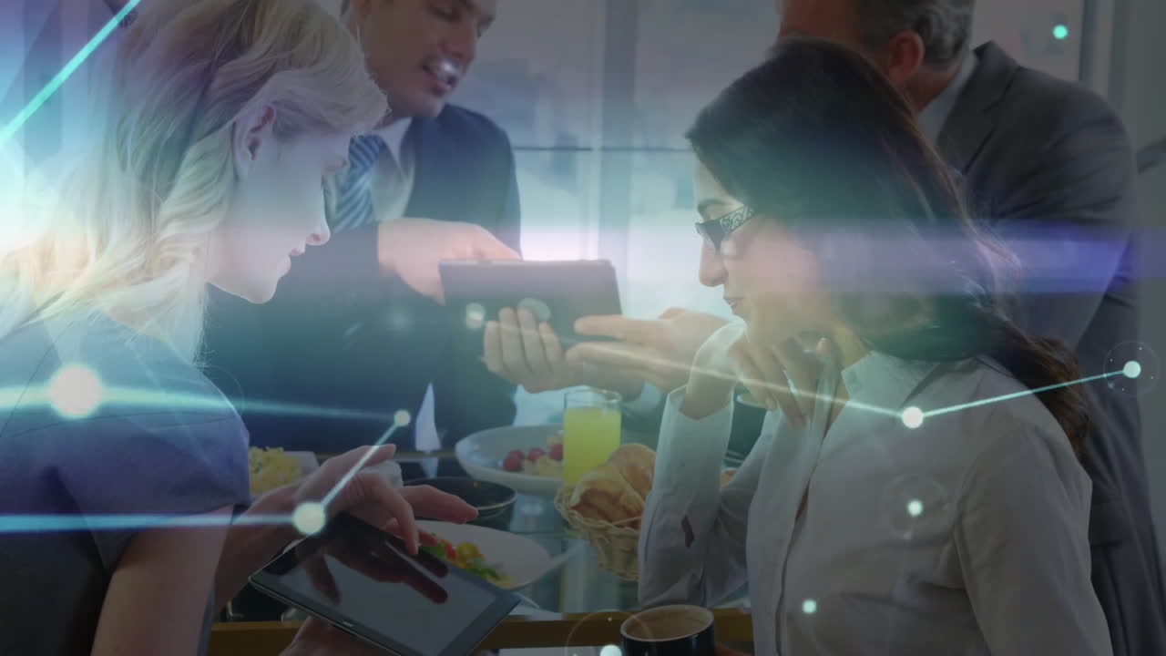 Four business professionals discussing around table in office, displaying interactive tablet graphs
