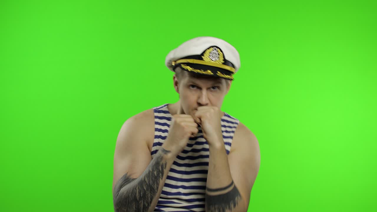 젊은 선원 근육이있는 남자가 주먹 싸움을 보여줍니다. 선원의 조끼를 입은 선원 남자