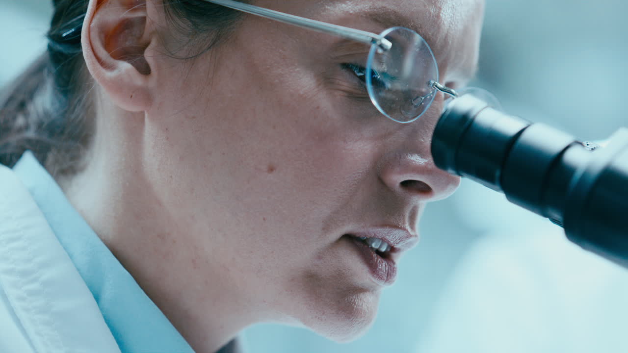 Scienziata di laboratorio che usa un microscopio e parla in un centro di ricerca