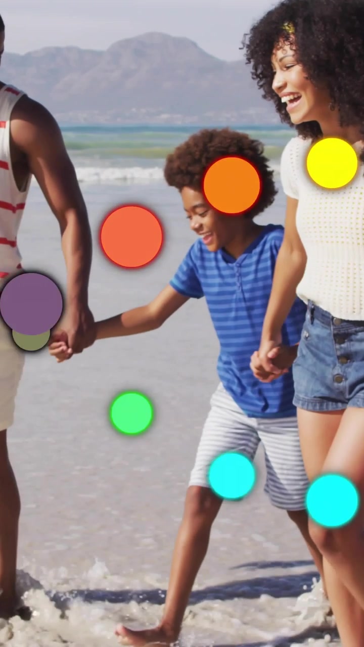 Vertical video: On arrival, parents lifting boy and running in surf, color dots floating for travel