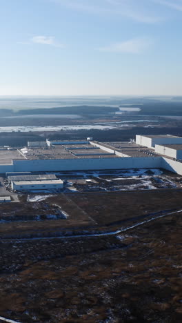 big territory of industrial factory surrounded by nature. view from above on the roofs of a modern plant in the countryside in winter. aerial view. vertical video