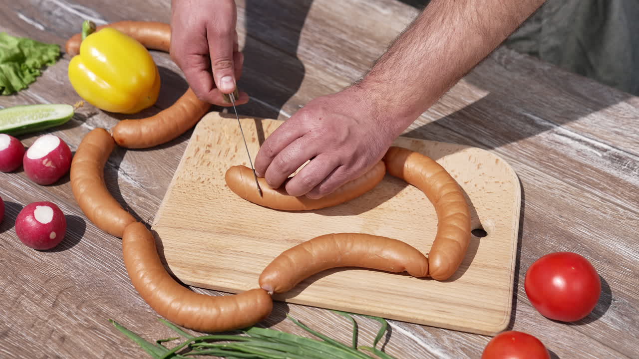 Man cutting sausages before grilling. Chef in doing incisions on hot dog sausages for picnic outdoors. Cooking and eating in nature. Top view.