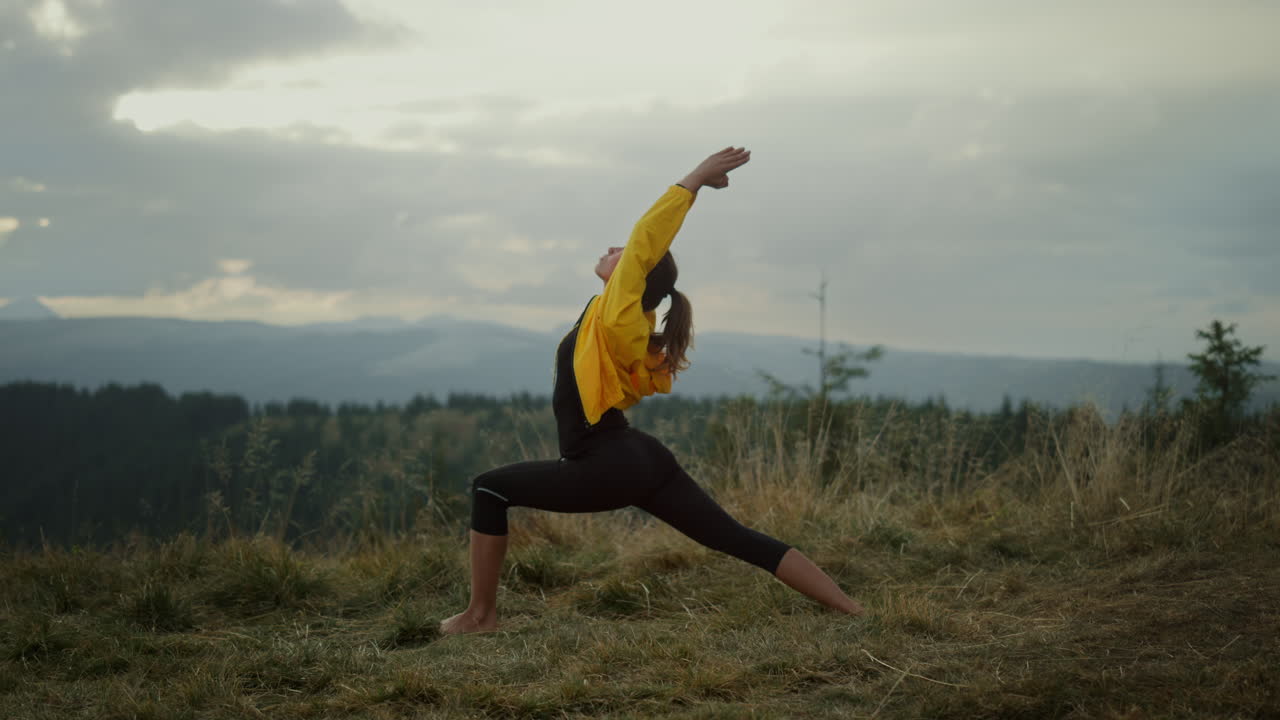mujer de yoga haciendo postura de guerrero en las montañas. chica flexible practicando yoga