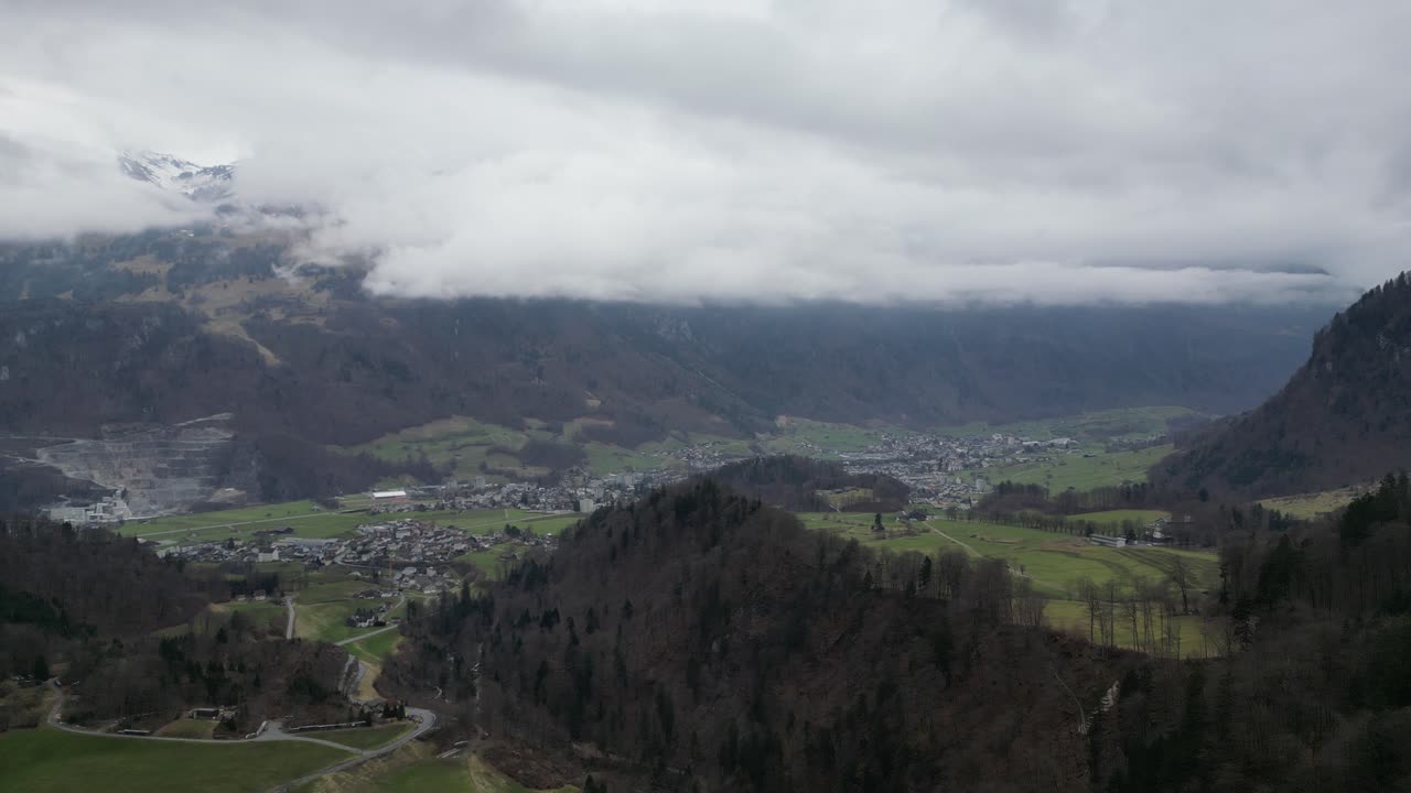 establecimiento aéreo de la idílica campiña europea ciudad rural en la base de las montañas cubiertas de nubes