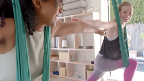 happy diverse fitness teenage girls in aerial yoga class in big white room, slow motion