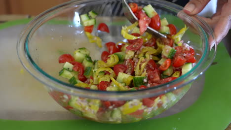 mixing dressing into tomato, pepperoncini, cucumber and shallots for a chopped salad - antipasto salad series