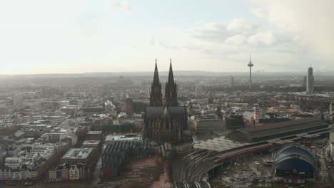 Aerial-panoramic-footage-of-large-city.-Train-arriving-to-main-train-station-next-to-historic-gothic-cathedral.-Cologne,-Germany