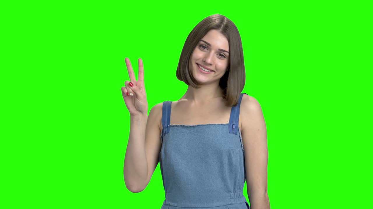 Giovane ragazza bruna carina mostra il gesto della vittoria