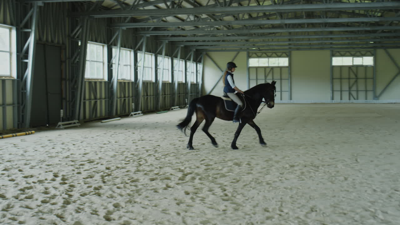Young Woman Riding Horse in Indoor Equestrian Arena
