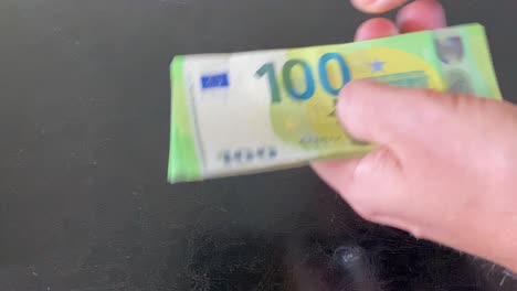 man hands pick up 100 euro banknotes and count them