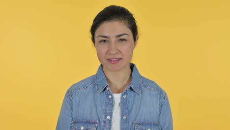 victory sign by young indian woman, yellow background