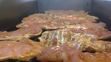 CLOSEUP-Footage-of-raw-chicken-while-cooked-on-the-grill-and-pouring-salt-and-pepper