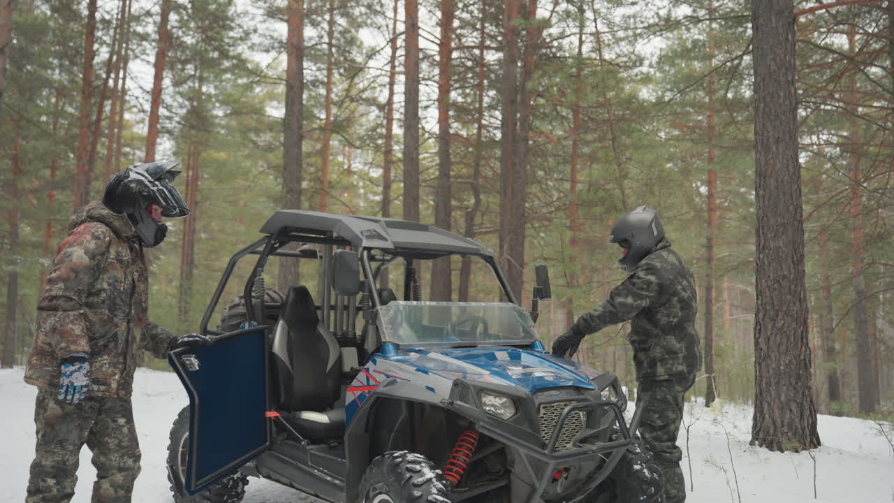 Ispezione di veicoli fuoristrada. L'equipaggio esamina attentamente le caratteristiche dell'ATV. Il team esamina i componenti dell'ATV in un paesaggio di pini innevati. Il gruppo controlla le caratteristiche di sicurezza dell'ATV in un ambiente di foresta innevata.