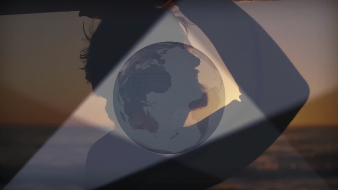 Man silhouette standing on coast at sunset, showing technology globe with dark diagonal frames