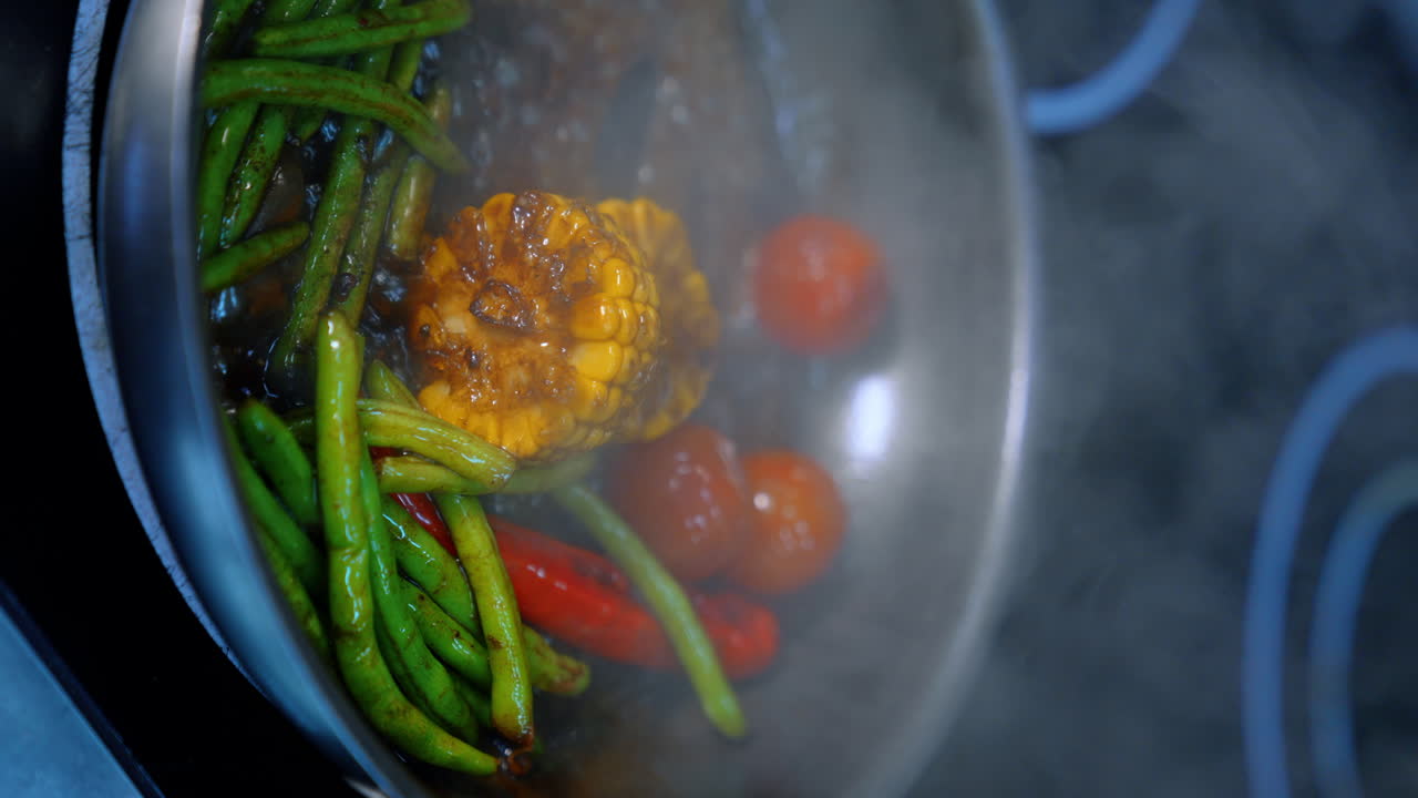 Beans, tomatoes, pepper, maize are stewed in soy sauce. Preparation of veggies in the frying pan. Close up. Vertical view.