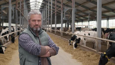 Camera-Focuses-On-A-Farmer-In-A-Farm-With-Cows-Around