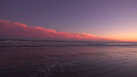 waves rolling on the sand under a purple red night sky -wide