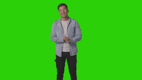 portrait of friendly casually dressed smiling young man against green screen