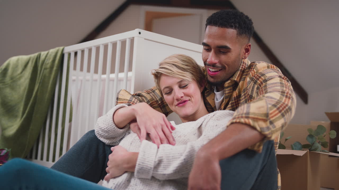 pareja amorosa esperando a un bebé abrazándose en la guardería de un nuevo hogar junto con mudarse en cajas