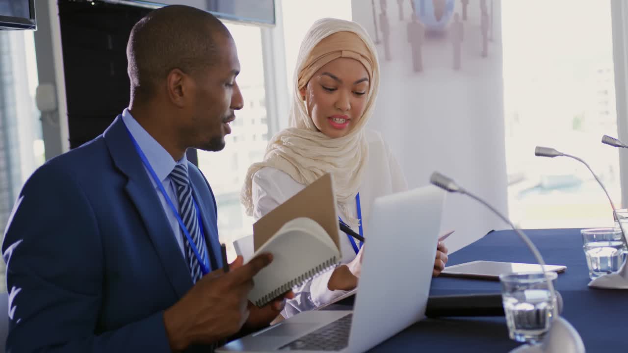 Two delegates talking making notes at a business conference