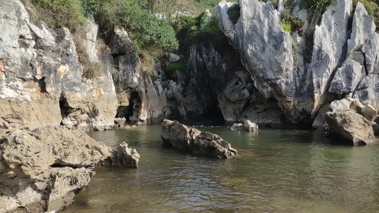 Rocky cove with clear water at Gulpiyuri beach, hidden gem in Asturias, Spain