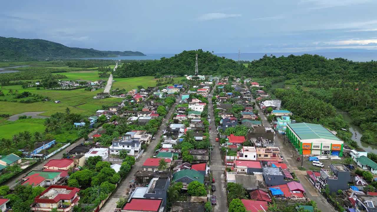 필리핀 카탄두아네스 외곽의 무성한 정글 내에 목가적인 열대 마을의 공중 전망을 구축합니다.