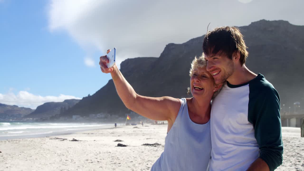 madre e hijo tomando una selfie desde el teléfono móvil en la playa