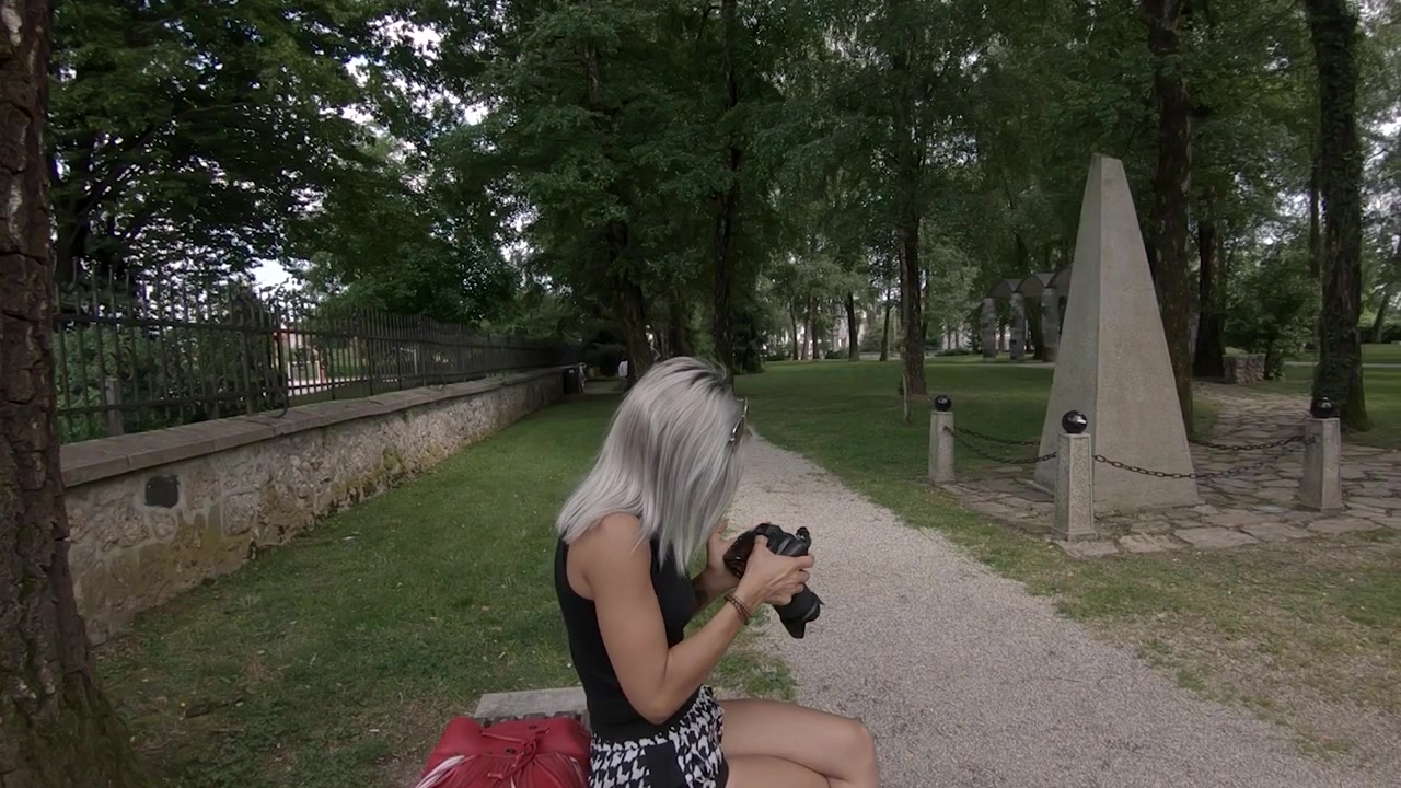 Câmera lenta de jovem, bela e atraente mulher loira vendo fotos na câmera no parque, Kranj, Eslovênia