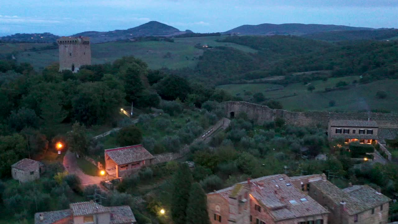 Sera a San Quirico d'Orcia, Toscana, Italia. Veduta aerea di case, torre e paesaggio italiano.