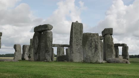 stonehenge, england, under a blue sky with white clouds and some beautiful black birds flying around the rocks