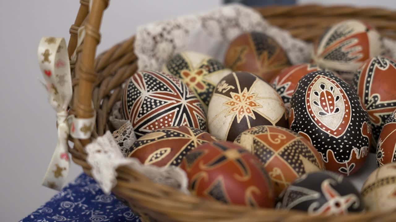 Close-up of colorful Easter eggs with white lace in a wicker basket