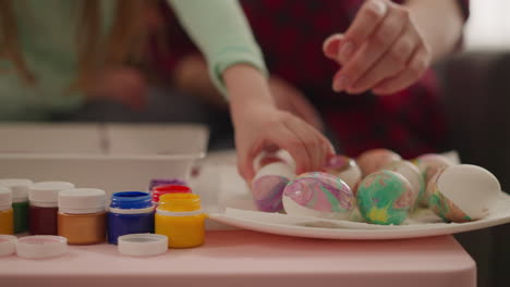 art teacher and student put colored eggs to dry in classroom