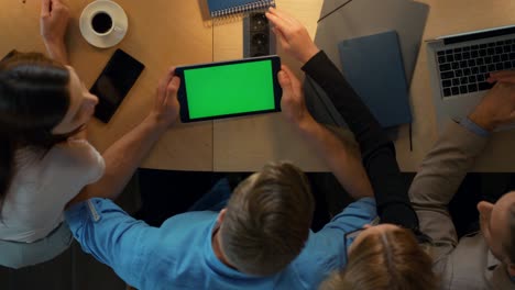 equipo trabajando juntos en el coworking. hombre mostrando a sus colegas la pantalla verde de la tableta.