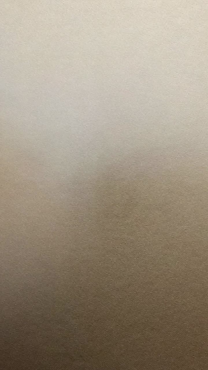 Video verticale: lente della fotocamera che scorre su una superficie beige chiaro in una stanza, mostrando la sfocatura