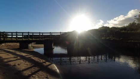 time lapse sunset clouds mirrored under wooden bridge flowing beach creek