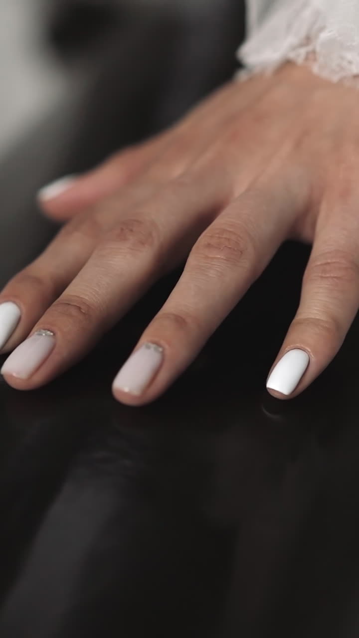 Manicured hand of graceful young bride in wedding dress with frillings touches railing closeup. Woman at bridal ceremony in festive events palace