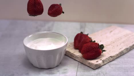 super cámara lenta de fresas frescas que caen en la crema a 1000 fps