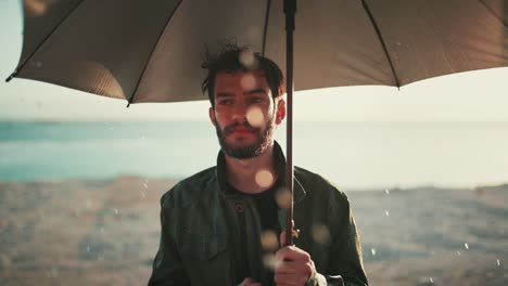 emotional israeli man stands in rain with umbrella in desert, backlit by sunset