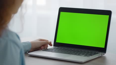 niña desconocida viendo videos en línea en una computadora portátil con pantalla clave de croma verde, sentada en casa, espacio libre