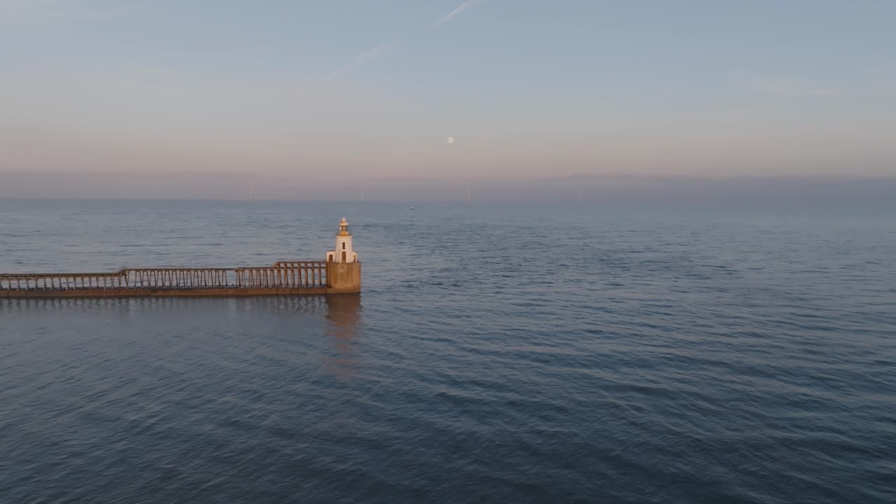 A tranquil aerial view of Blyth Lighthouse under the rising moon and serene evening skies.