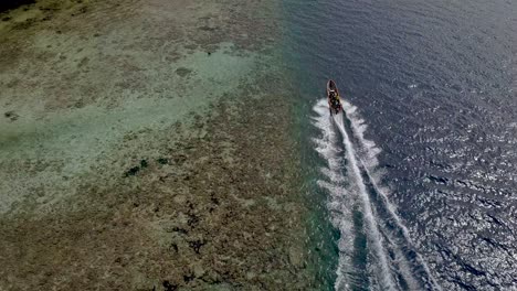 aerial shot following a commuter boat transporting people alongside coastline in papua new guinea