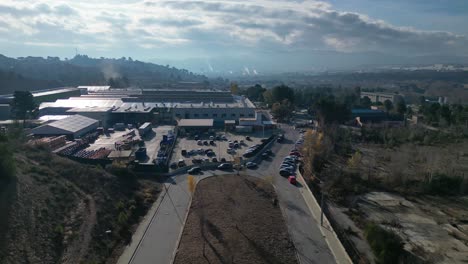 industrial area near abrera, barcelona with roads and parked cars, under a cloudy sky, aerial view