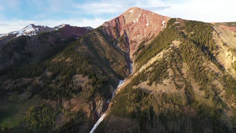 Ein-Farbenfroher-Krönender-Berggipfel-Mit-Einem-Schneeschmelzwasserfall,-Der-In-Der-Mitte-Herunterläuft,-Ist-An-Einem-Hellblauen-Himmelstag-In-Colorado-In-Der-Nähe-Von-Crested-Butte-Zu-Sehen